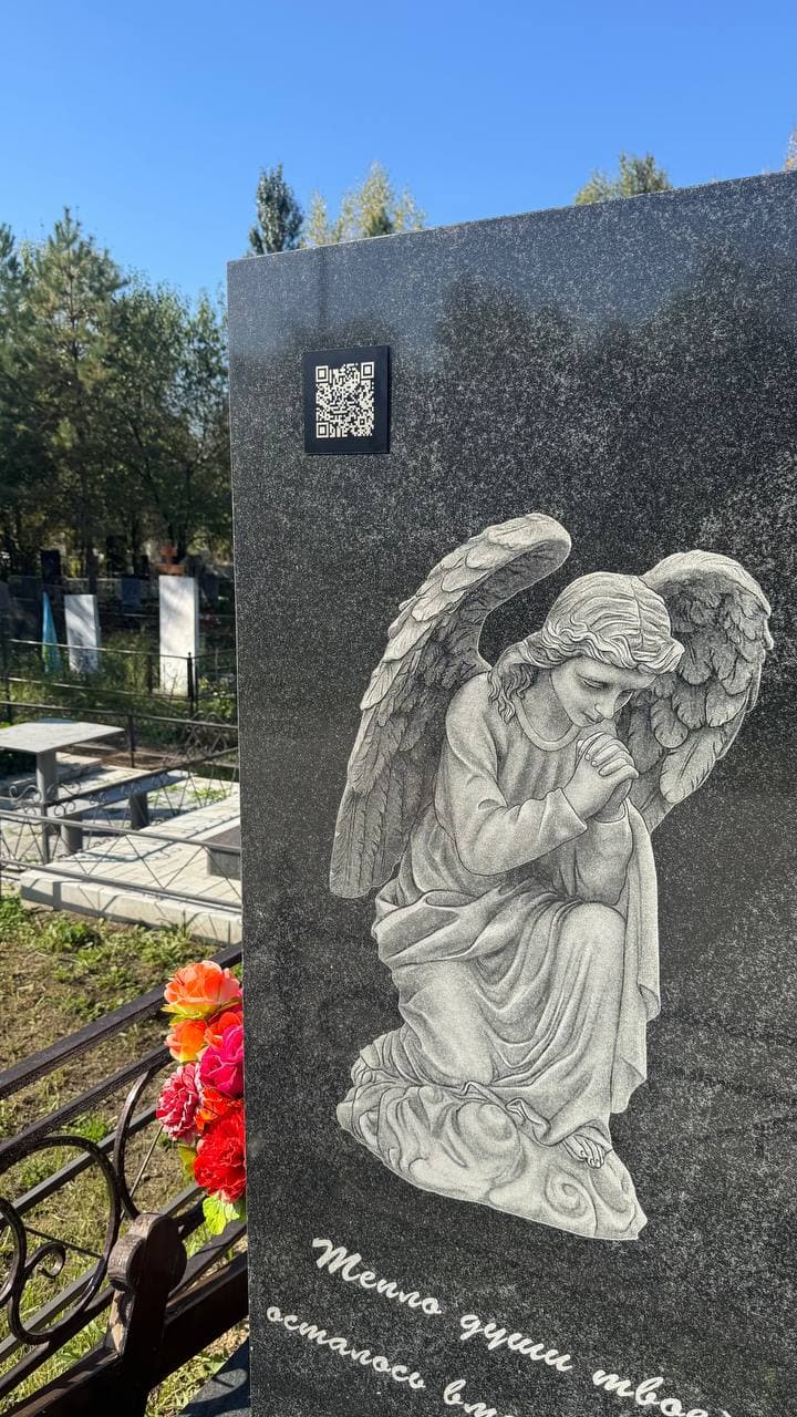 Чёрная табличка с QR‑кодом на гранитном памятнике с ангелом