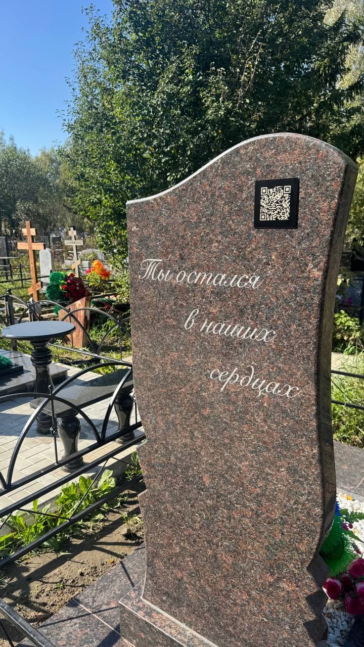 Чёрная табличка с QR‑кодом на памятнике из красного гранита