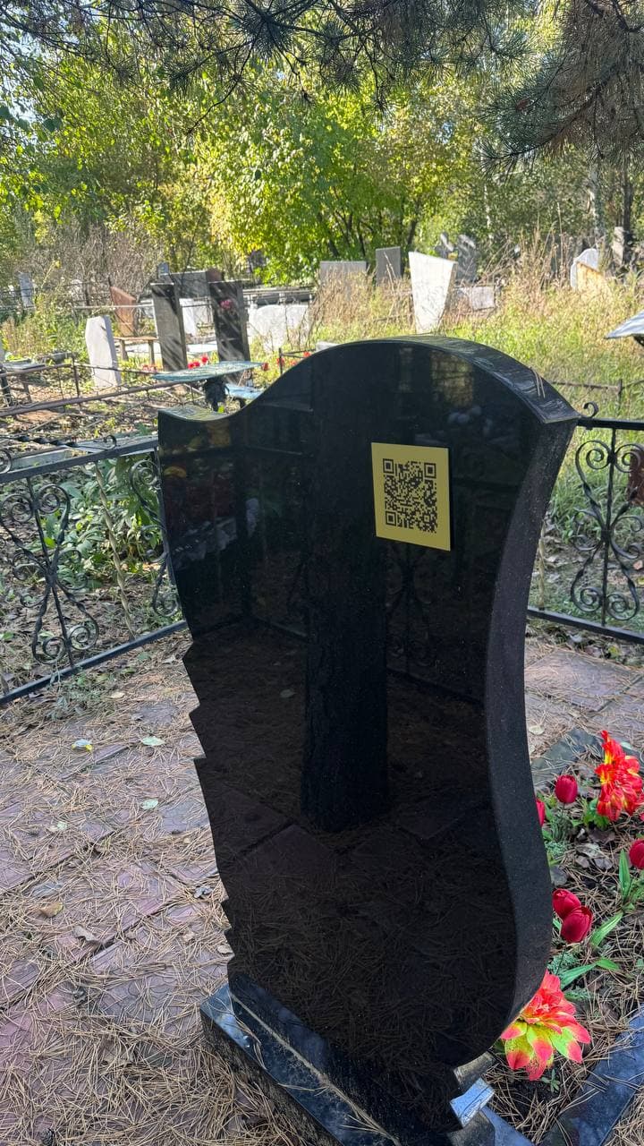Золотистая табличка с QR‑кодом на памятнике из чёрного гранита