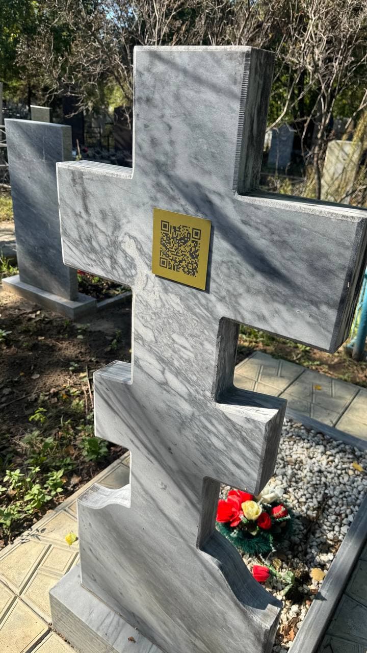 Золотистая табличка с QR‑кодом на мраморном кресте