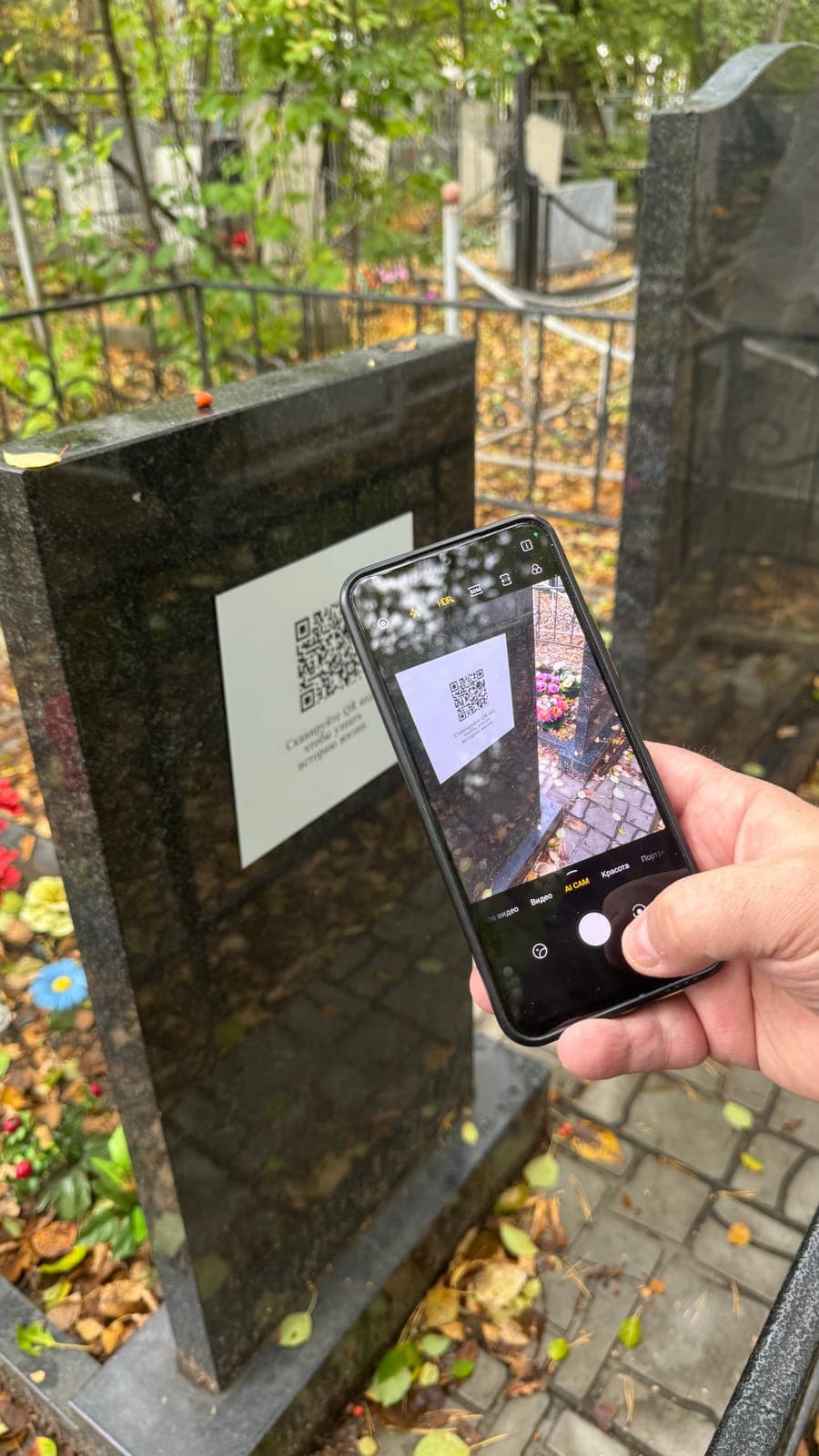 Человек сканирует QR‑код на памятнике камерой телефона